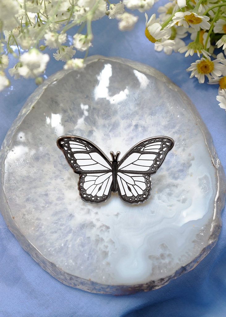White monarch enamel pin placed on Agate stone