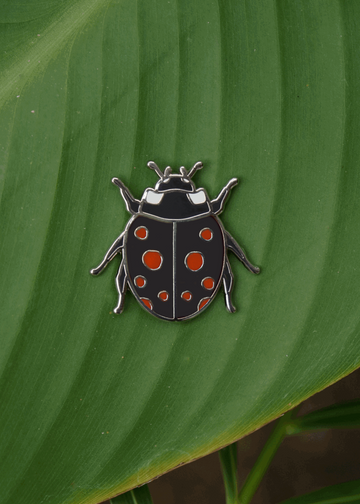 Black ladybug pin with red spots on leaf