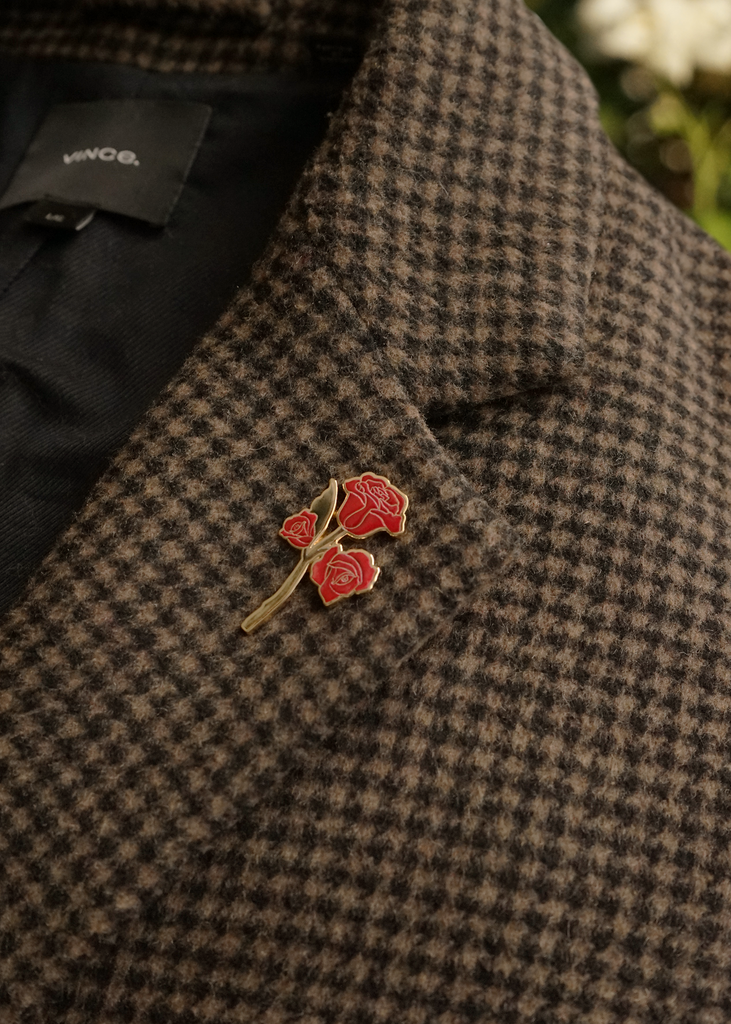 Red rose pin on a houndstooth-patterned coat with a blurred background