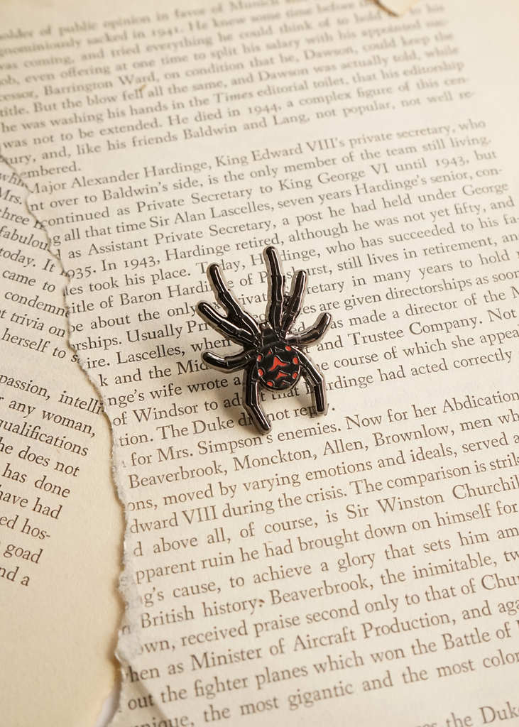 Black widow spider mini pin on page of book