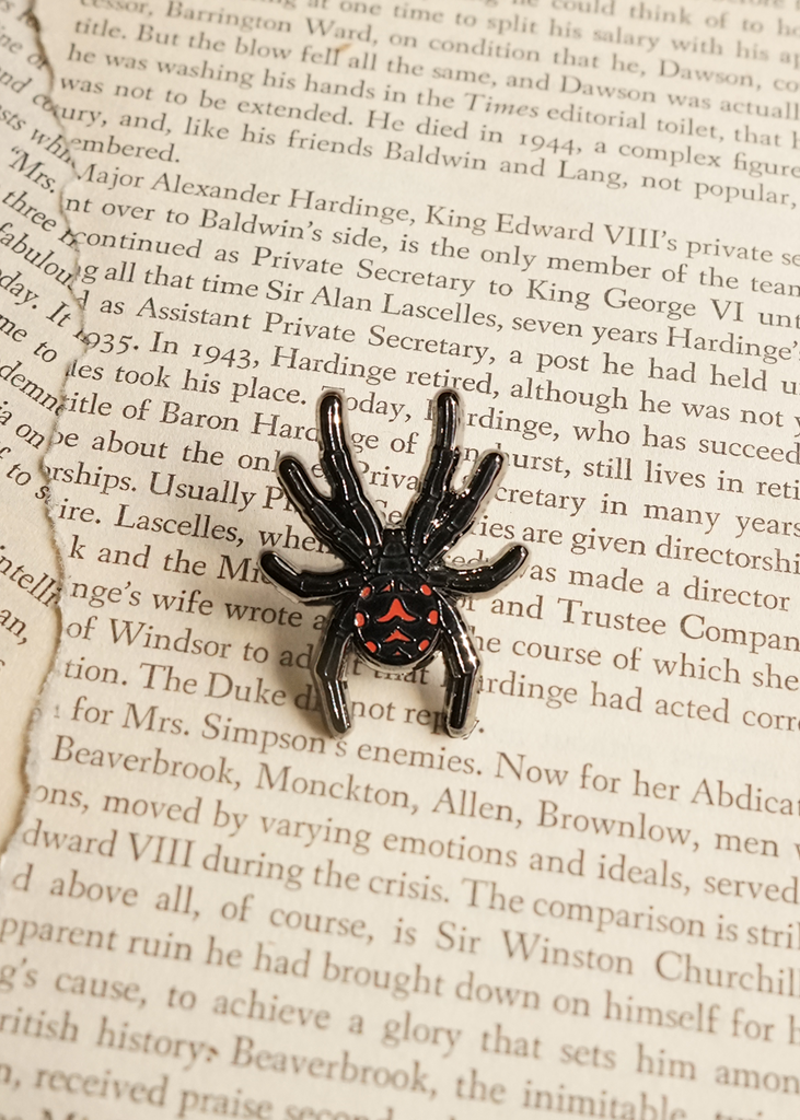 Black widow spider mini pin on page of book