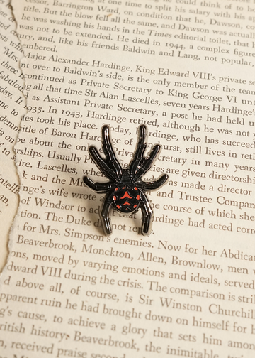 Black widow spider mini pin on page of book