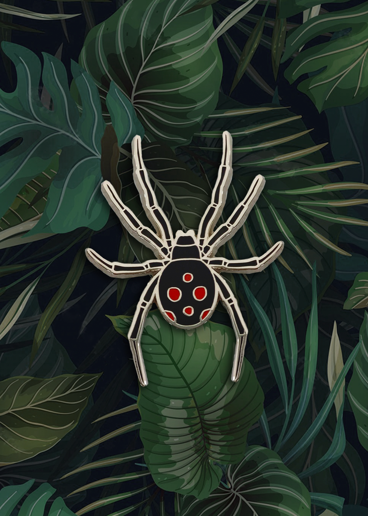 Black widow pin in front of tropical backdrop