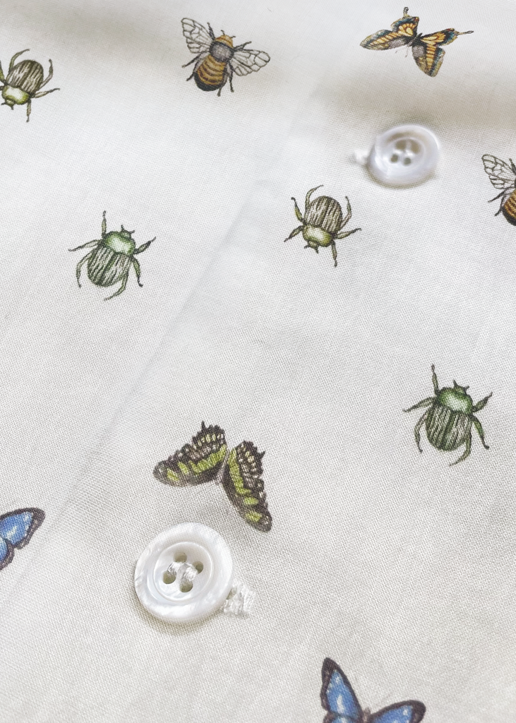 Fabric with insect patterns and white mother of pearl buttons on a textured background