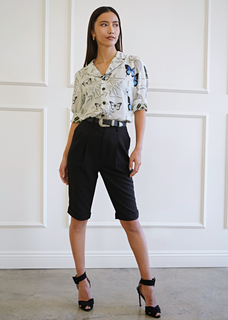 Full view of model wearing 3/4 sleeve atlas shirt paired with mid length trousers in black