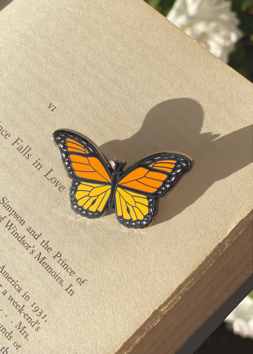 Orange monarch enamel pin on book