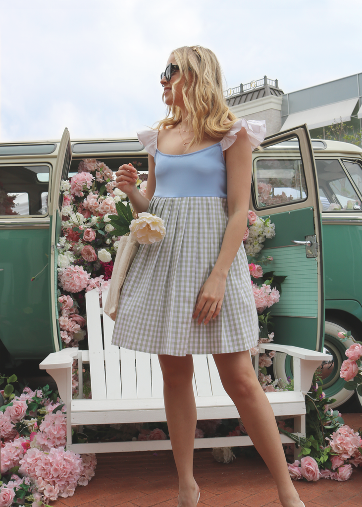 Front view of model wearing winged Marili dress in Serenity blue bodice and olive green and white pleated gingham skirt pattern